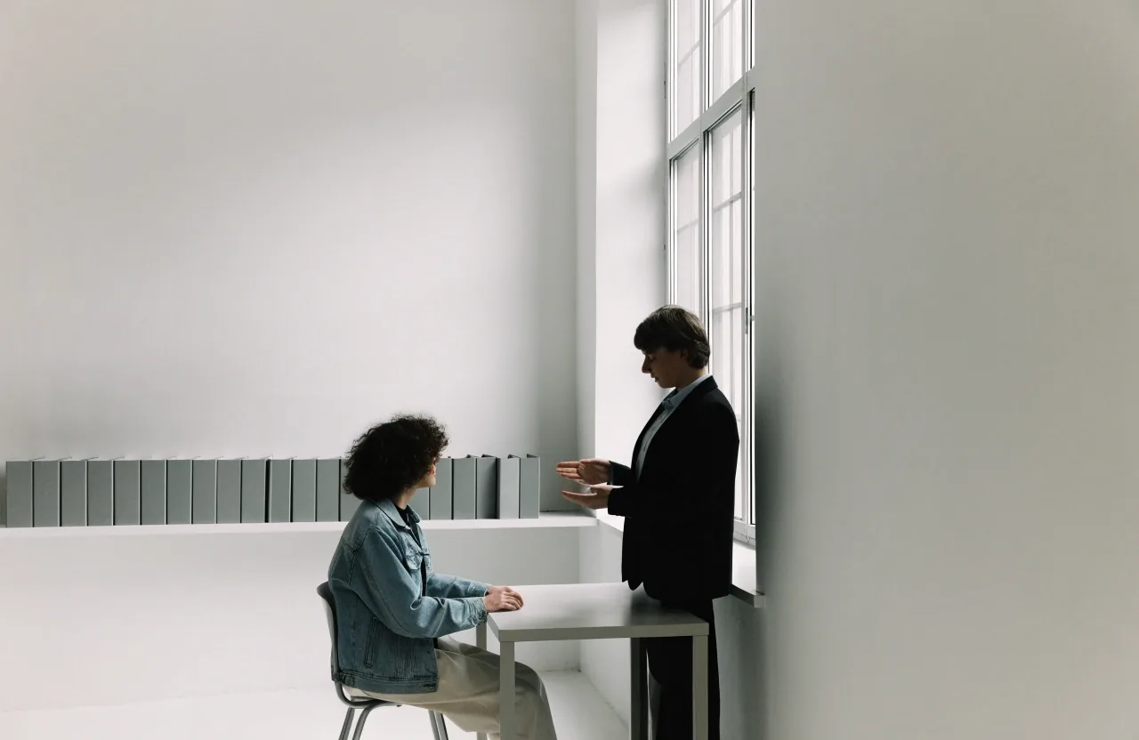 Two colleagues discussing a policy document at a window in a quiet office