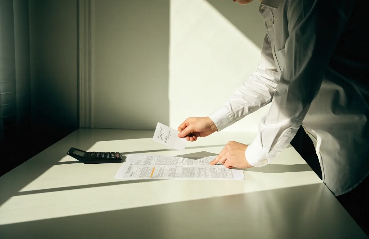 An editor writing a date and numbered list by hand on a policy form at a bright desk